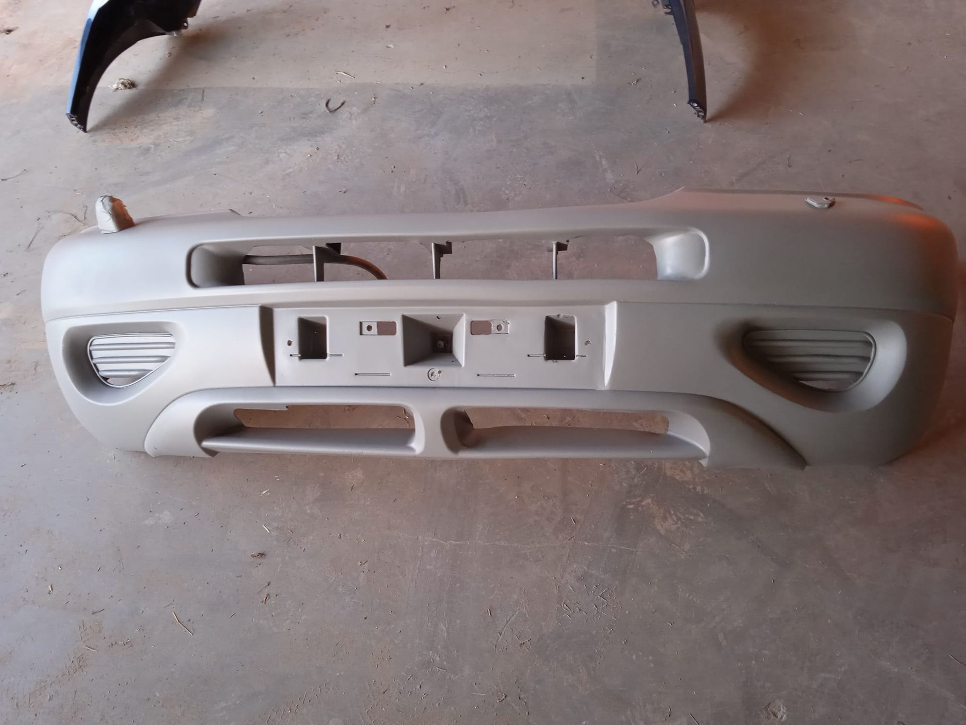 Parachoques de coche plateado sobre una superficie de hormigón.