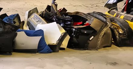 Pila de piezas de automóvil, incluidos parachoques y puertas, sobre una superficie de color bronce.