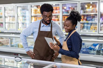Jeune homme devant des rayons de produits frais.