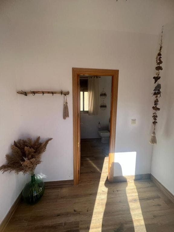 Una habitación con suelo de madera y una puerta que conduce a un baño.