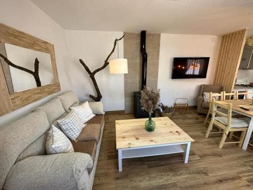 Una sala de estar con sofá, mesa, sillas y televisión.