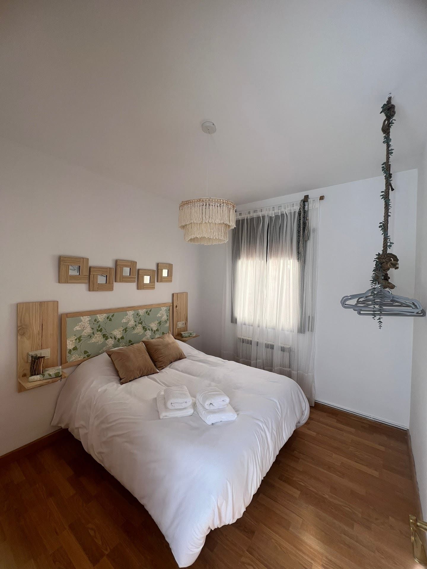 Un dormitorio con una cama y una ventana con una percha colgando del techo.