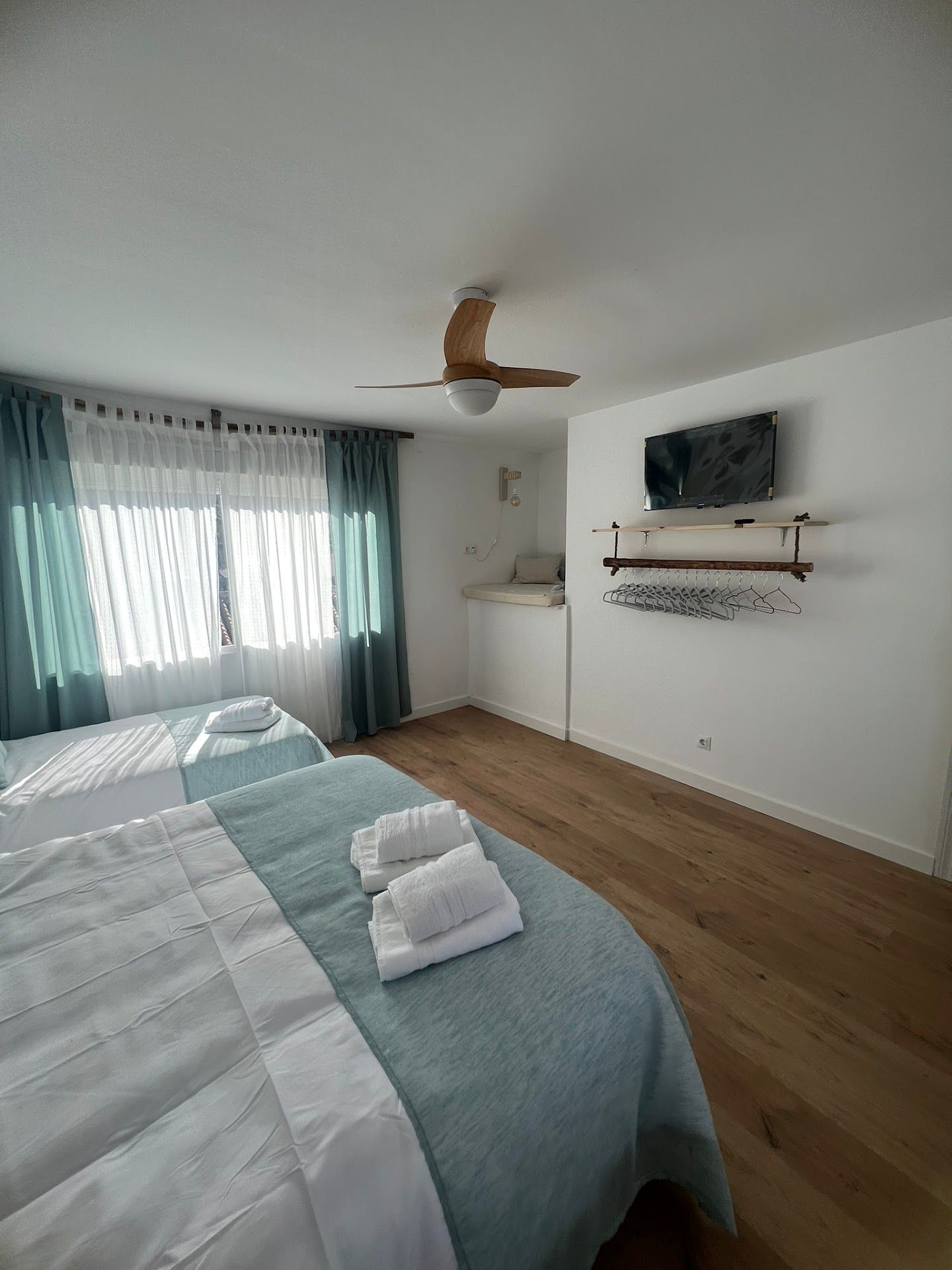 Un dormitorio con dos camas, un ventilador de techo y un televisor de pantalla plana.