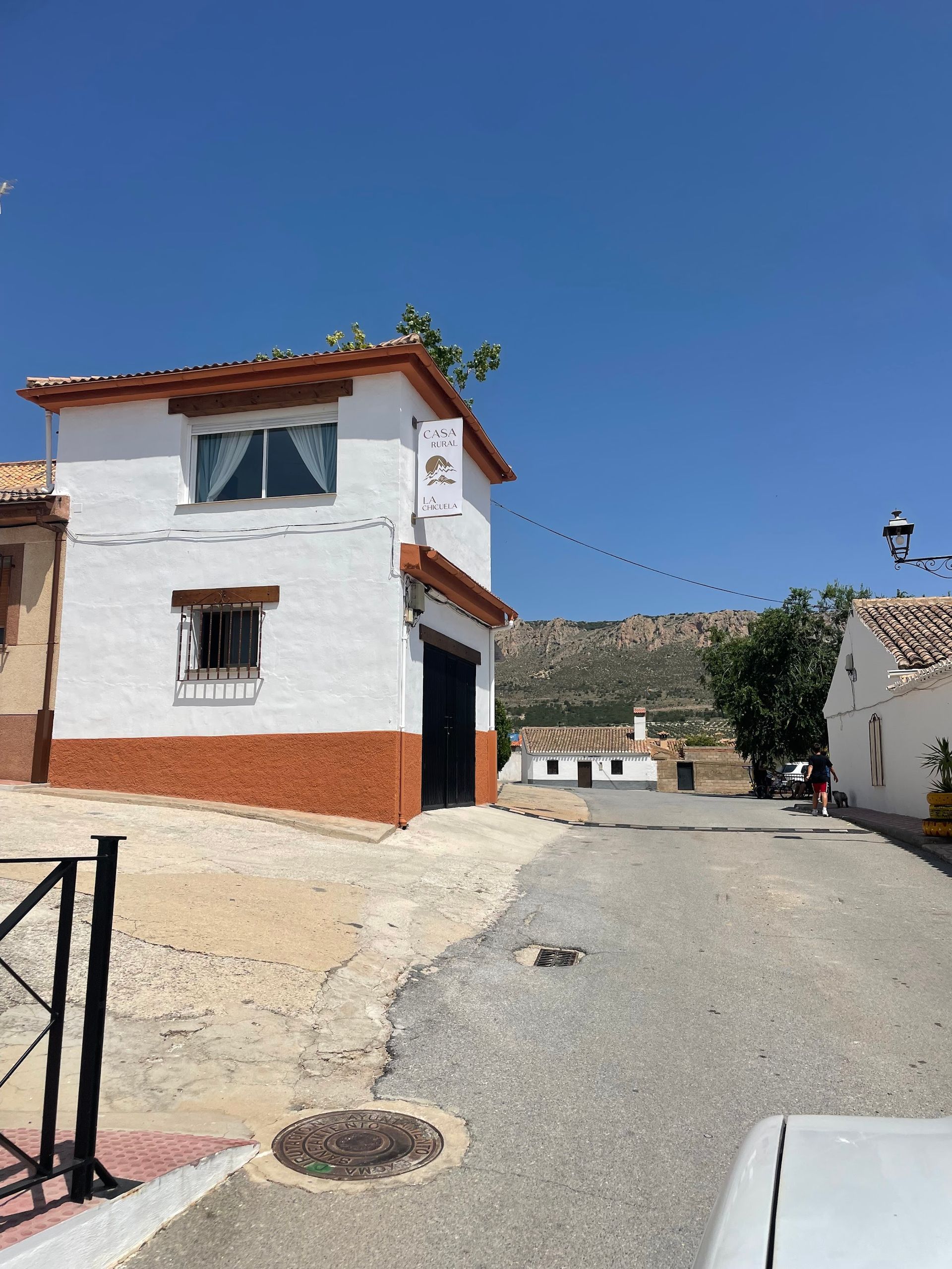 Una casa blanca con techo rojo está en la esquina de una calle.