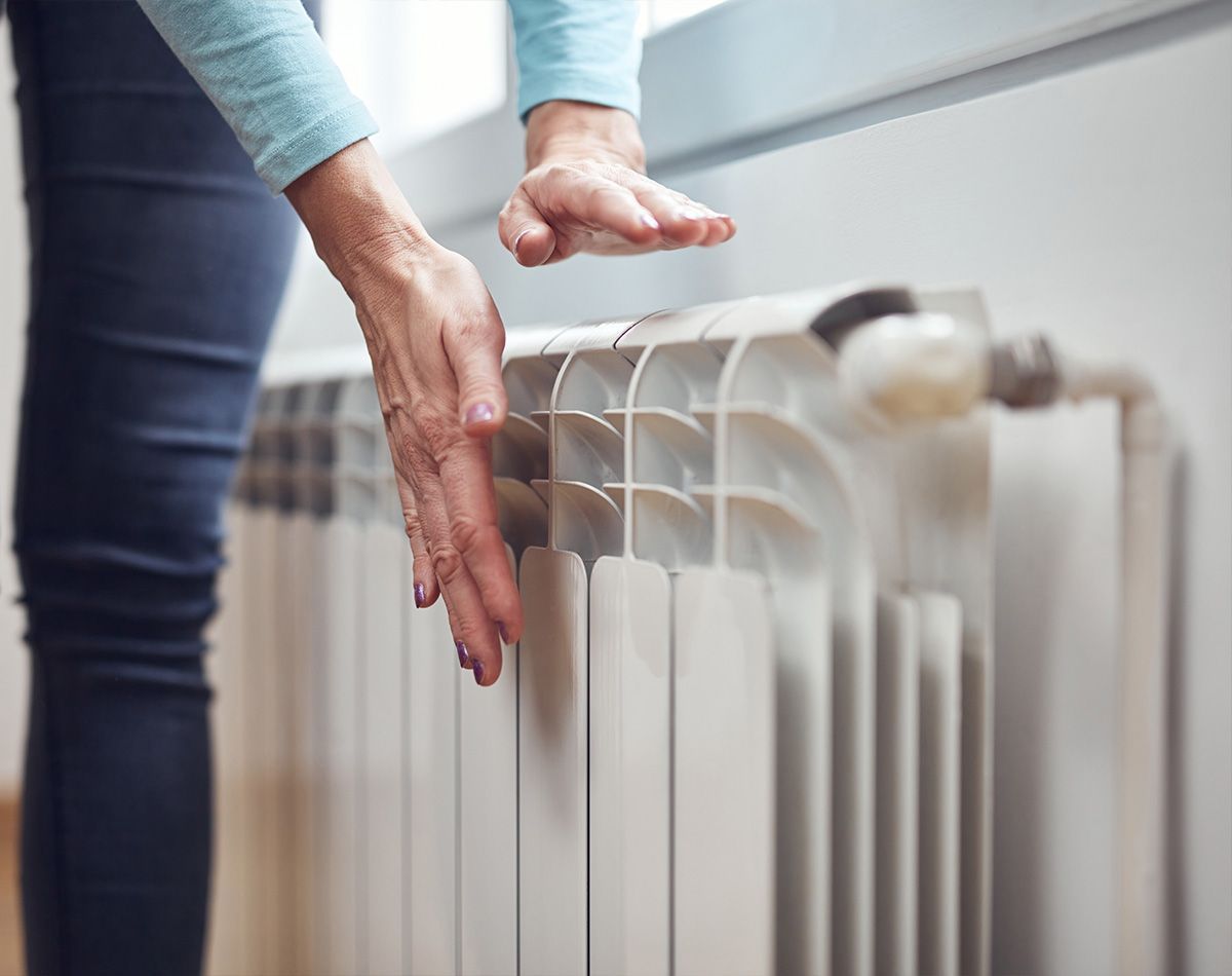 Mains posées au6dessus d'un radiateur diffusant de la chaleur