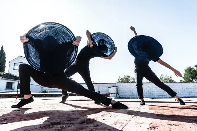 Un grupo de personas está bailando frente a un edificio blanco.