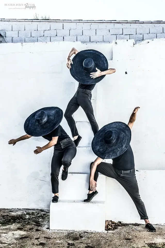 Tres hombres con sombreros negros están parados en unas escaleras.
