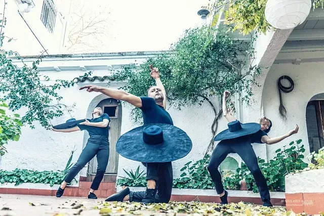 Un grupo de personas está bailando frente a un edificio blanco.