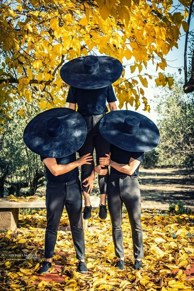 Tres personas con sombreros negros están paradas en una pila de hojas.