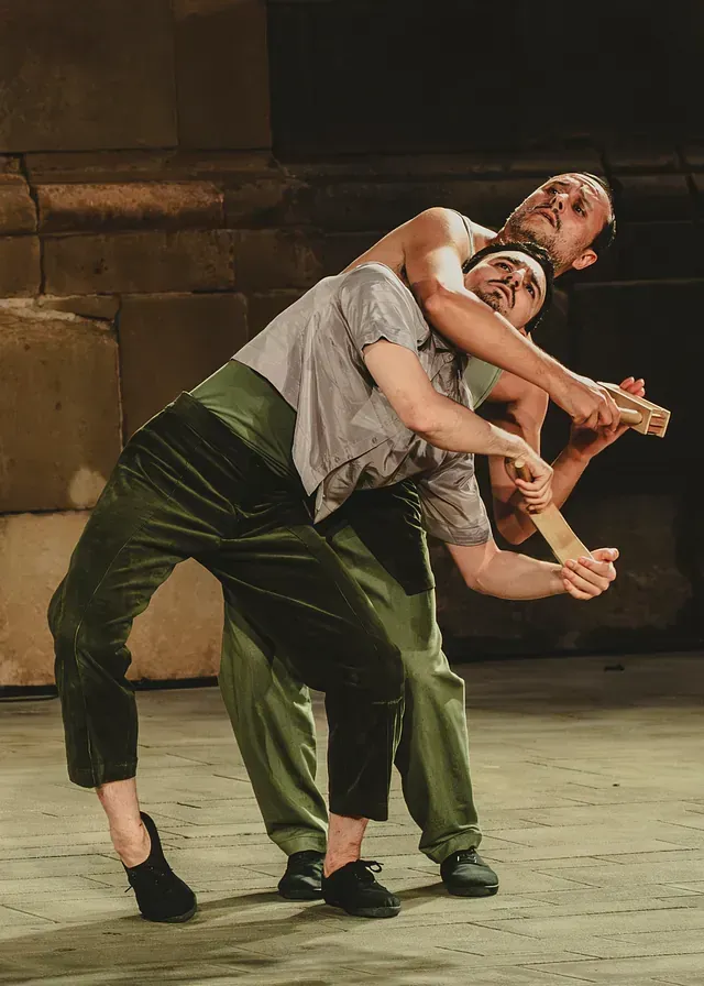 Un hombre lleva a otro hombre en su espalda mientras baila en un escenario.