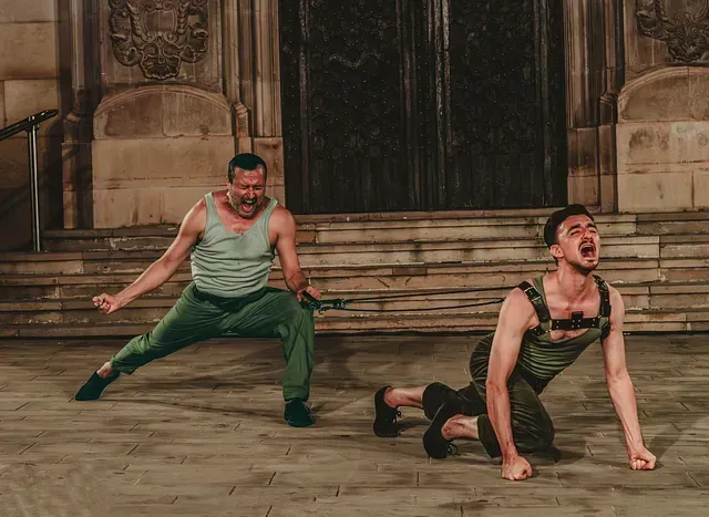 Dos hombres están bailando en un escenario frente a un edificio.