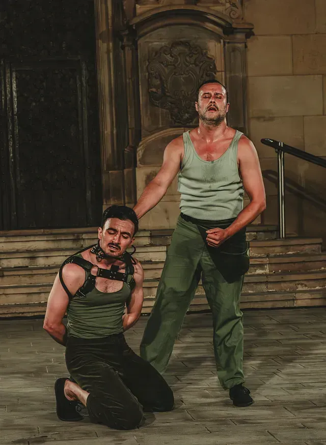 Un hombre con una camiseta verde sin mangas está arrodillado junto a otro hombre con una camiseta verde sin mangas.