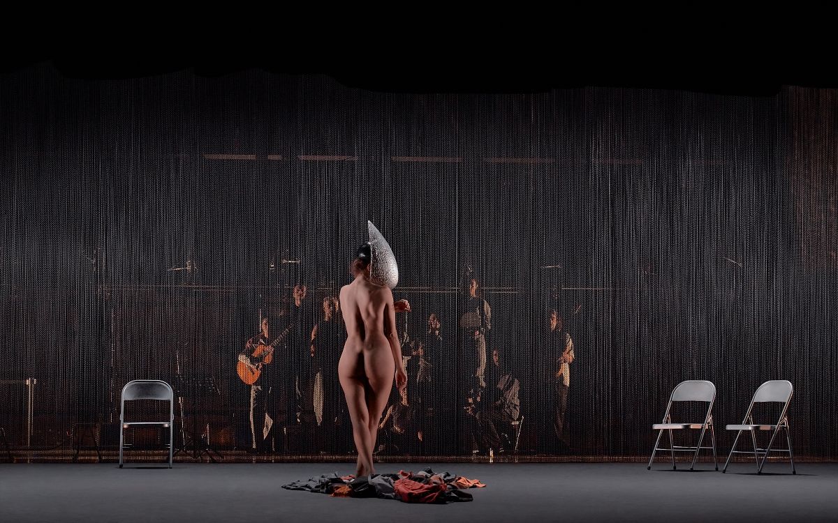 Un hombre con una camisa negra está parado frente a un cartel cultural de 24h la hora.
