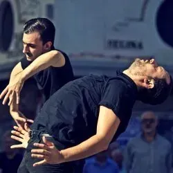 Dos hombres están bailando juntos en un escenario frente a una multitud.