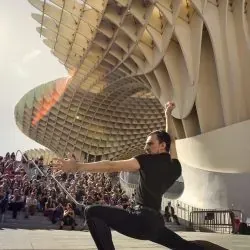 Un hombre está haciendo un split frente a un gran edificio.
