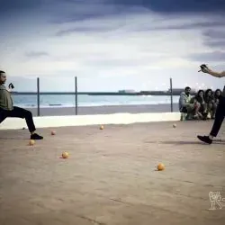 Dos hombres están jugando a la petanca en una playa.