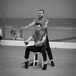 Dos hombres están sentados en un taburete en la playa.