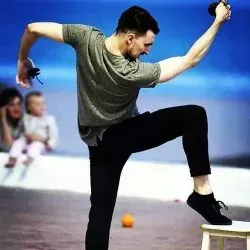 Un hombre está de pie sobre una pierna en un taburete.