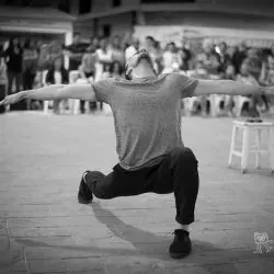 Un hombre está de pie sobre una pierna con los brazos extendidos en una fotografía en blanco y negro.