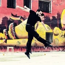 Un hombre está bailando delante de un mural en una pared.