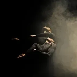 Un hombre está flotando en el aire en una habitación oscura con los brazos extendidos.