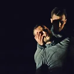 Dos hombres están parados uno al lado del otro en la oscuridad.