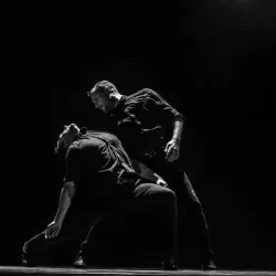 Dos hombres están bailando en un escenario en una foto en blanco y negro.