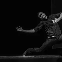 Un hombre está bailando en un escenario en una foto en blanco y negro.