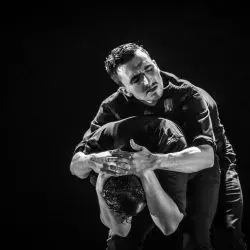 Un hombre sostiene a otro hombre en sus brazos en una fotografía en blanco y negro.