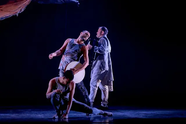 Un grupo de hombres está bailando en un escenario en una habitación oscura.