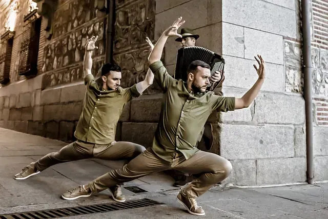 Dos hombres están bailando en la acera frente a un edificio.