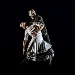 Un hombre sostiene a una mujer en sus brazos mientras bailan en un escenario.