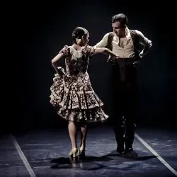 Un hombre y una mujer bailan flamenco en un escenario.
