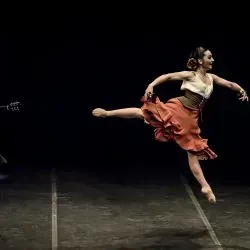 Una bailarina está saltando en el aire en un escenario.