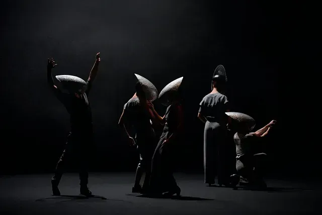 Un grupo de personas están de pie en una habitación oscura sosteniendo almohadas.