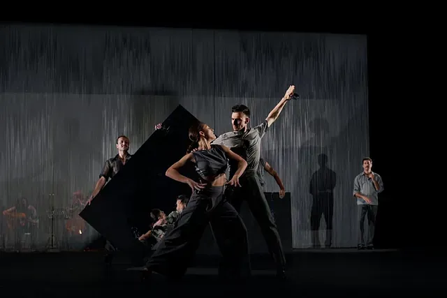 Un grupo de personas está bailando en un escenario en una habitación oscura.