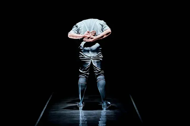 Un hombre está de pie en la oscuridad con las manos detrás de la espalda.