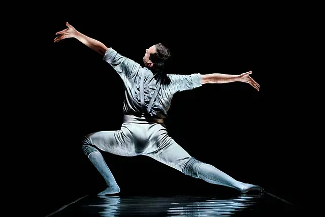 Un hombre está bailando en un escenario con los brazos extendidos.