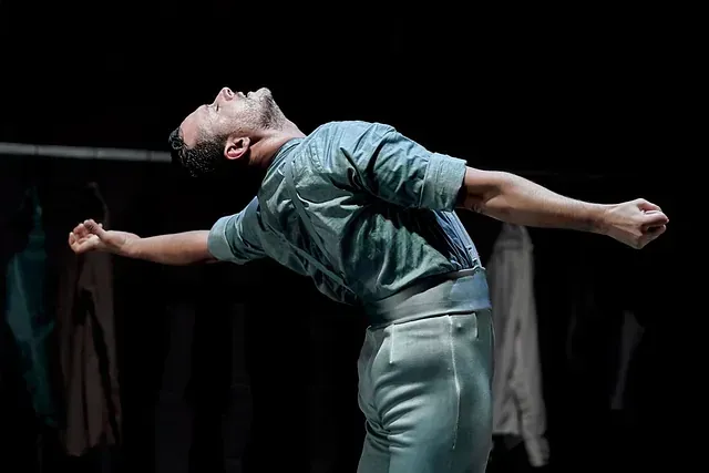Un hombre está bailando en un escenario con los brazos extendidos.