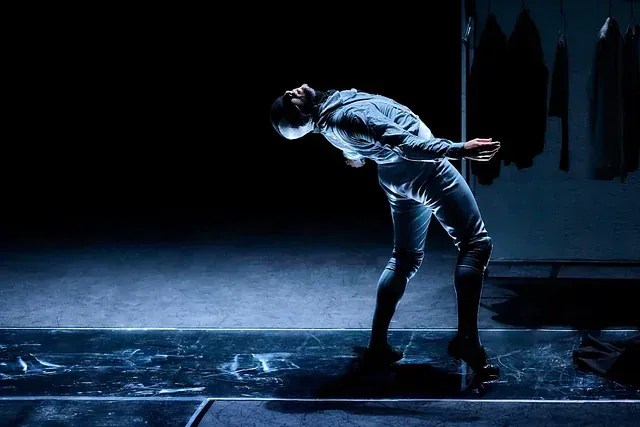 Un hombre está inclinado sobre un escenario en una habitación oscura.