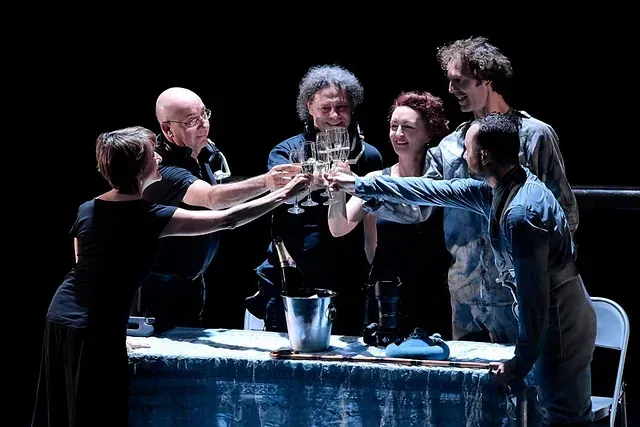 Un grupo de personas están de pie alrededor de una mesa brindando con copas de champán.