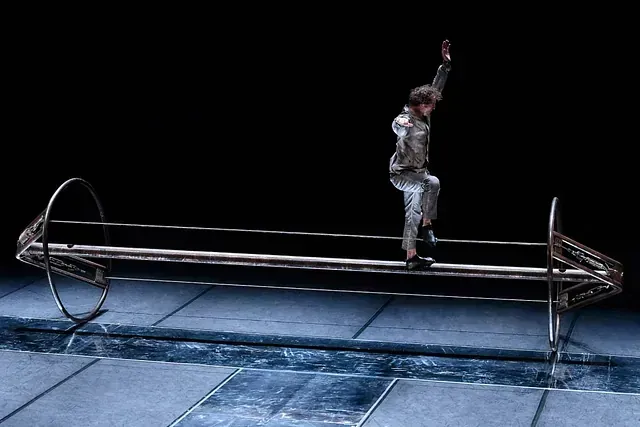 Una persona está parada sobre una estructura de metal con flechas apuntando en direcciones opuestas.