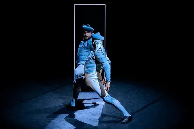 Un hombre con un traje azul está parado frente a un espejo.