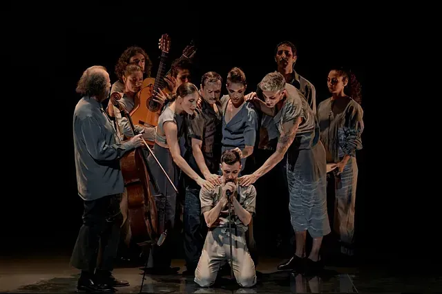 Un grupo de personas está de pie alrededor de un hombre en un escenario.