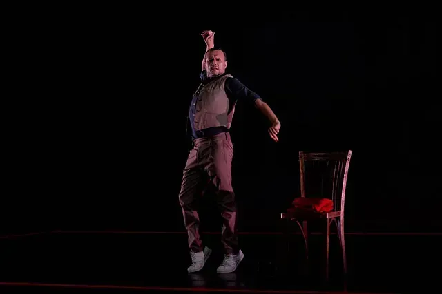 Un hombre está bailando en un escenario al lado de una silla.