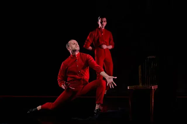 Dos hombres con monos rojos bailan en un escenario.