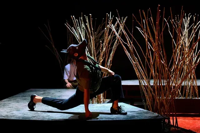 Una persona está bailando en un escenario delante de un montón de palos.