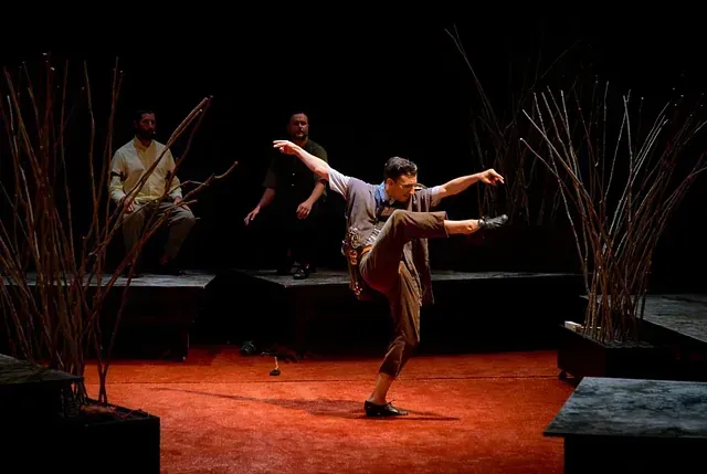 Un hombre está bailando en un escenario frente a un grupo de personas.