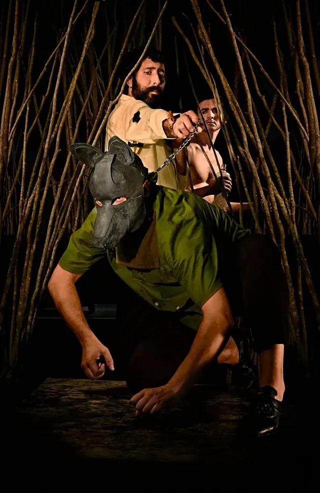 Un hombre que lleva una máscara de lobo está arrodillado junto a otro hombre.