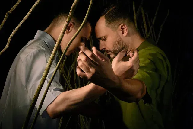 Dos hombres se abrazan en una habitación oscura.